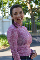 Woman wearing a purple patterned long-sleeve equestrian shirt outdoors with trees in the background