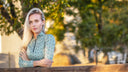 Woman standing behind a wooden fence with trees at equestrian stables in Cape Town South Africa